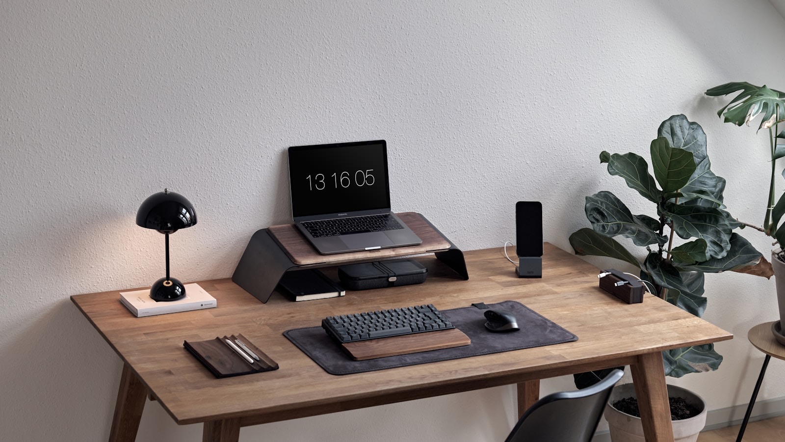 Aufgeräumter Arbeitsplatz mit Laptop, Bildschirm und Pflanze