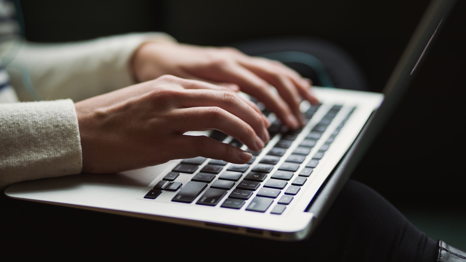 Close-up of hands typing on a laptop keyboard