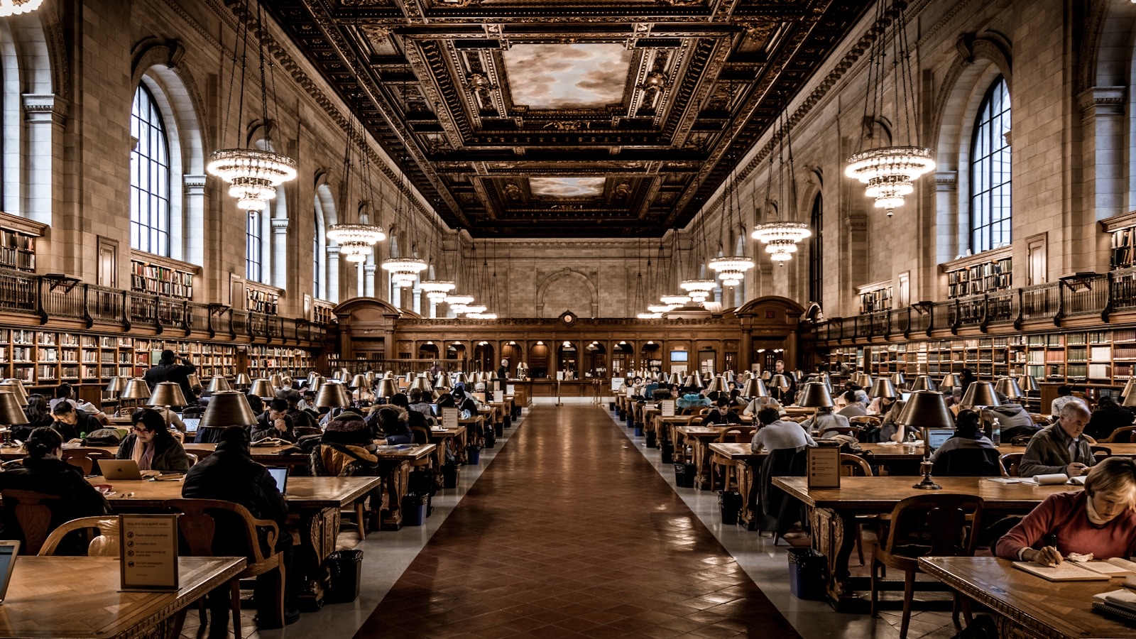 Large public reading room with long tables and bookshelves