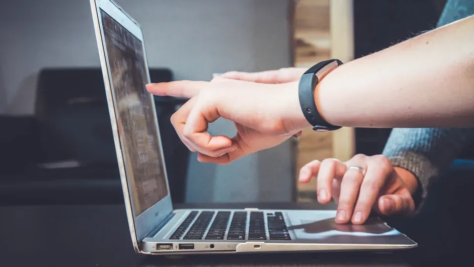 Zwei Personen zeigen während einer Inhaltsprüfung auf einen Laptopbildschirm