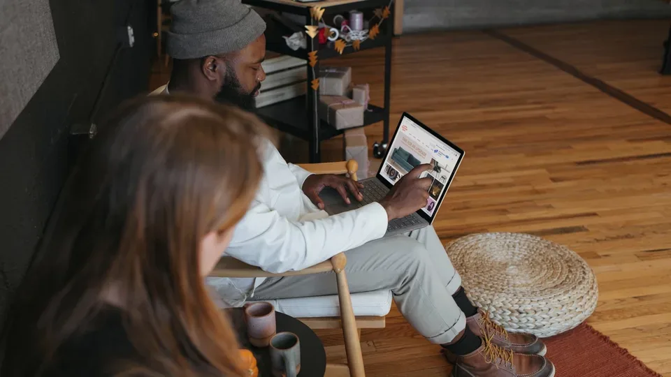 Zwei Personen arbeiten in einem hellen Raum an Laptops