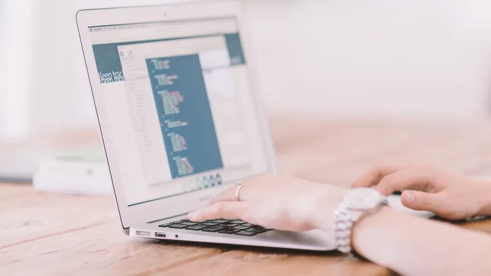 Hände bedienen einen Laptop mit einer geöffneten Codeansicht
