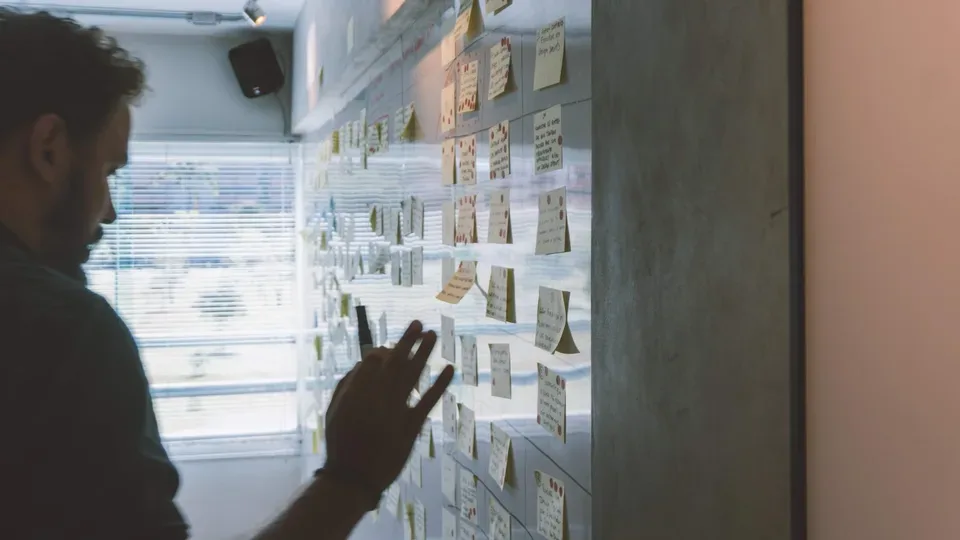 Person ordnet Haftnotizen auf einer großen Workshop-Wand