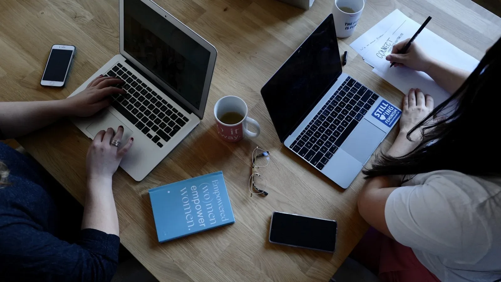 Zwei Kolleginnen arbeiten gemeinsam mit Laptops an einem Tisch